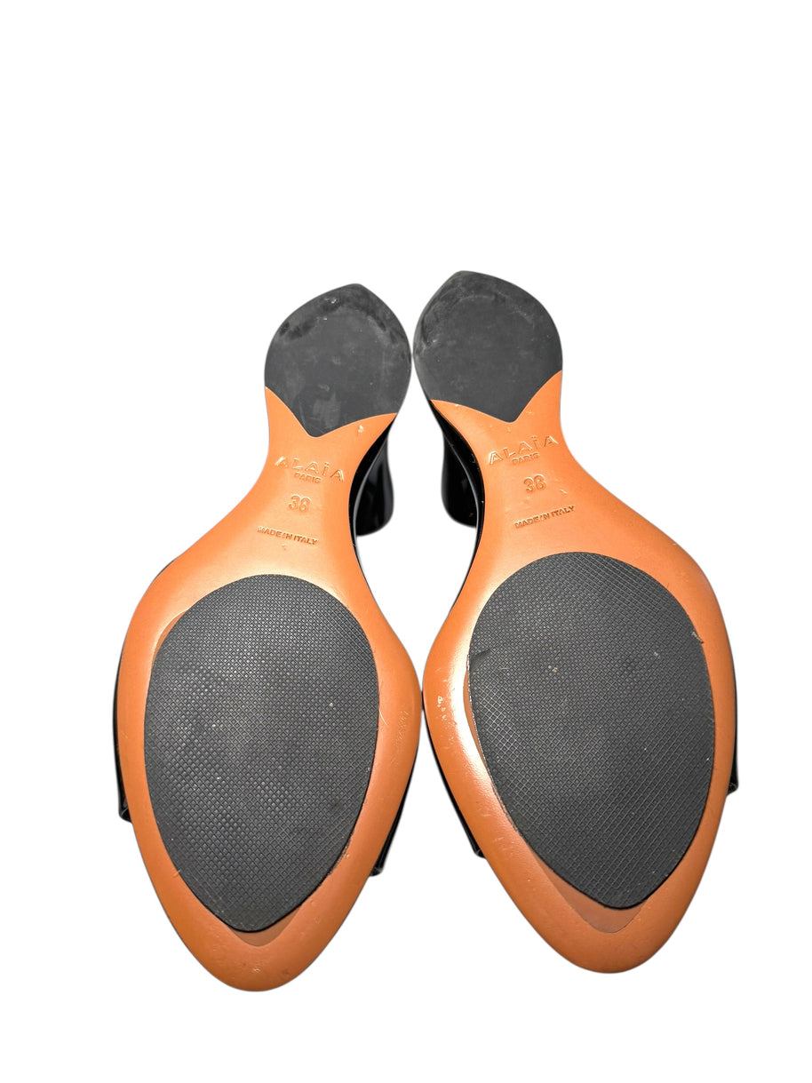 Pair of Alaia black patent wedge mule shoes soles with Brand 'Alaia' and size '38' and 'made in italy' stamped on soles on a white background