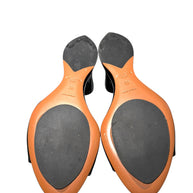 Pair of Alaia black patent wedge mule shoes soles with Brand 'Alaia' and size '38' and 'made in italy' stamped on soles on a white background