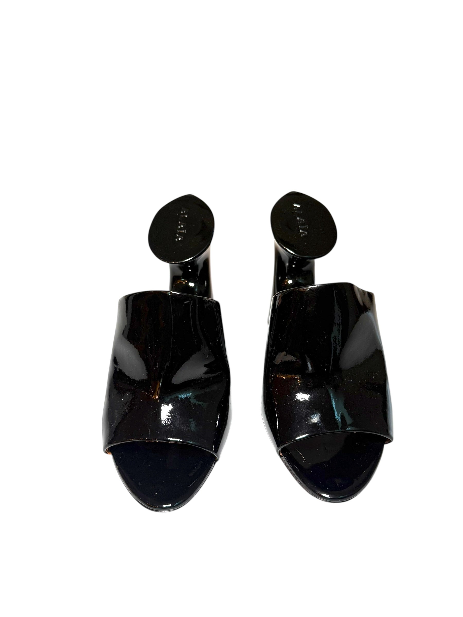 Pair of Alaia black patent high-heeled shoes front view on a white background