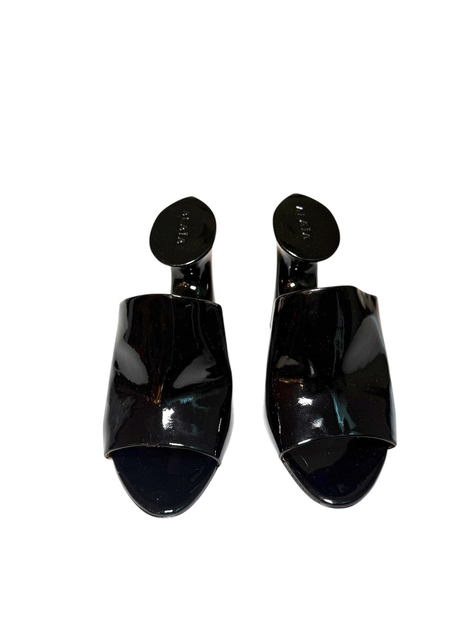 Pair of Alaia black patent high-heeled shoes front view on a white background