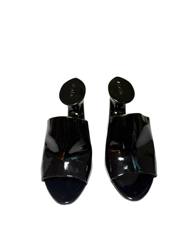 Pair of Alaia black patent high-heeled shoes front view on a white background