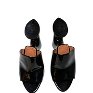 Black Alaia patent leather mules overhead view with peep toes  and Alaia brand label on a white background