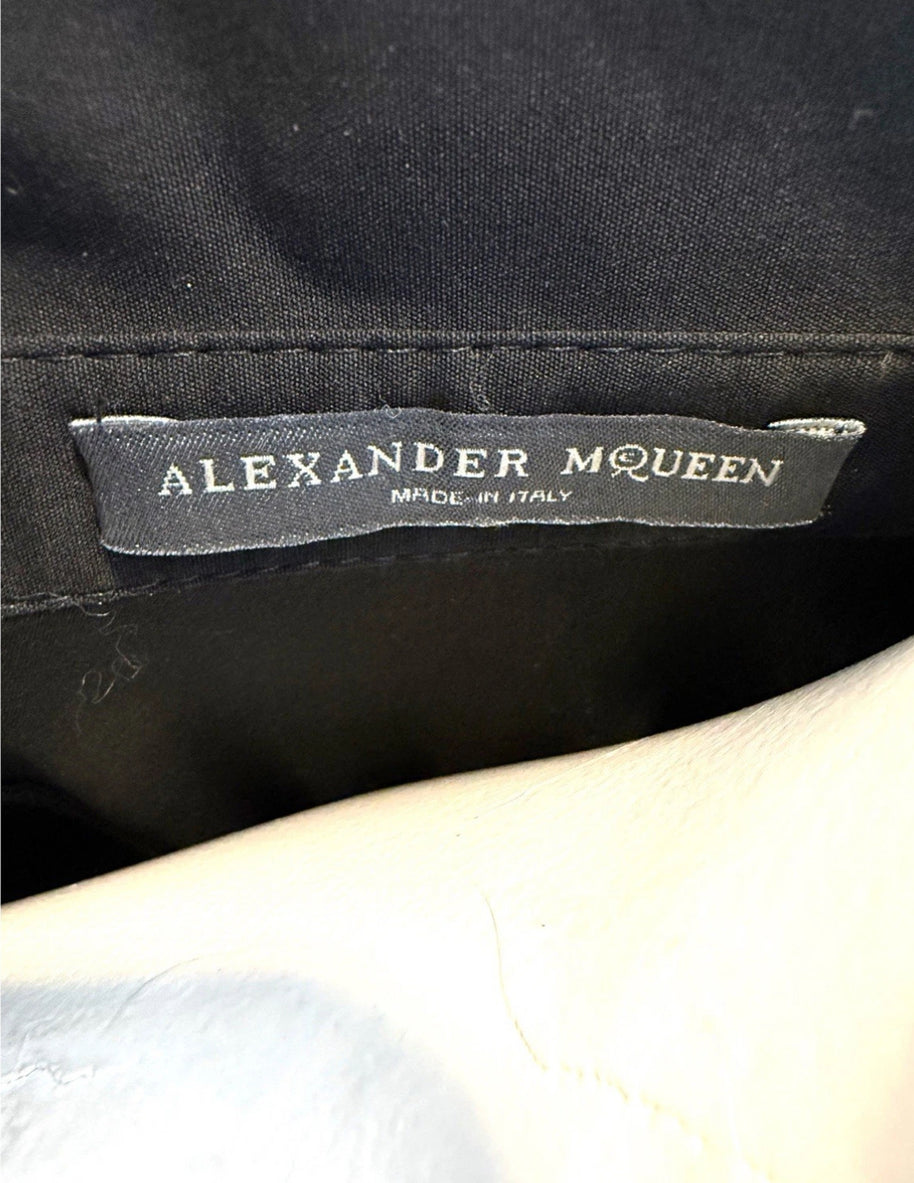 Alexander McQueen label on a black shirt dress with a white background