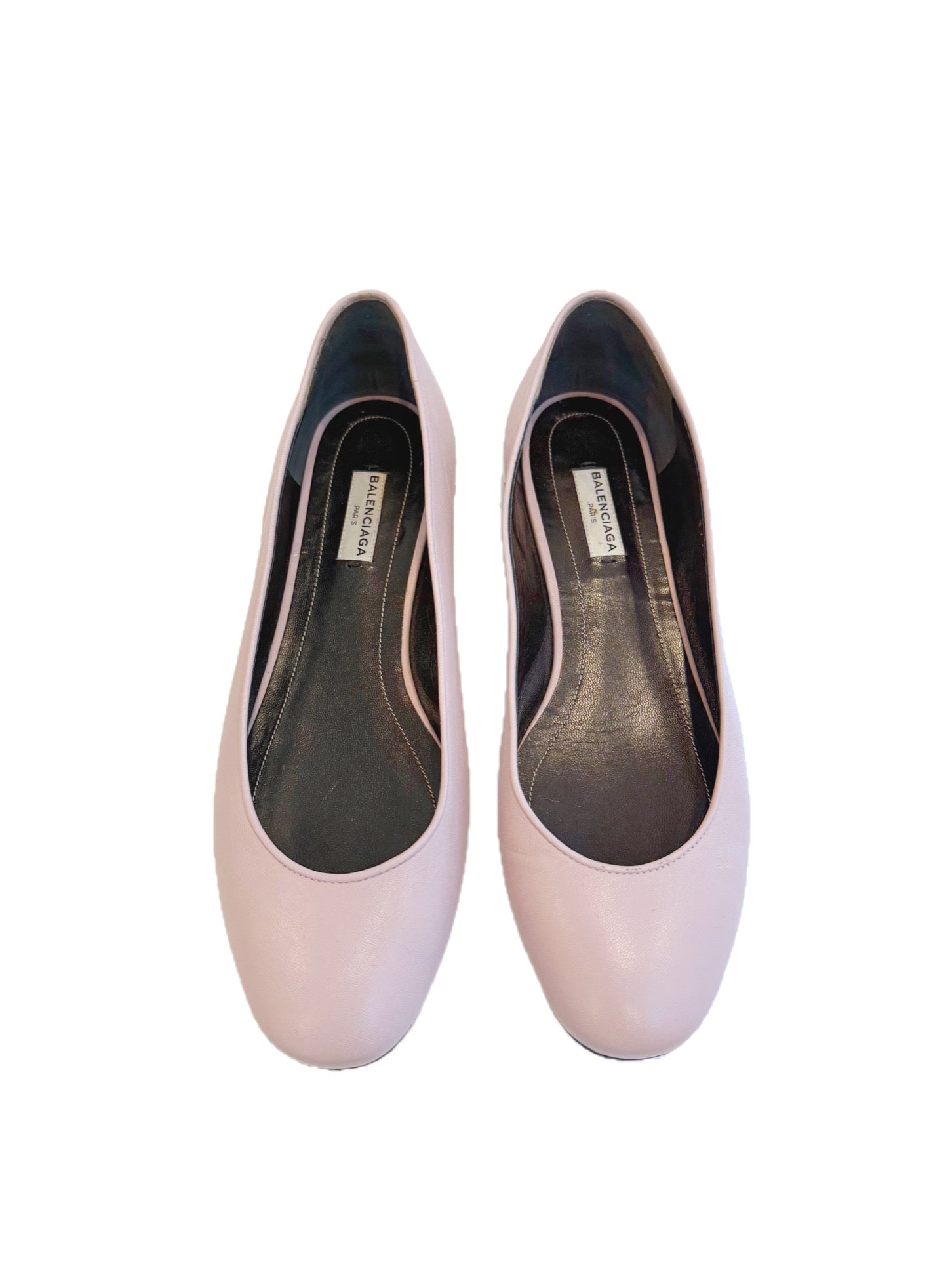 Top view of powder pink Balenciaga lambskin flats showing the rounded vamp and black leather interior with Balenciaga logo.