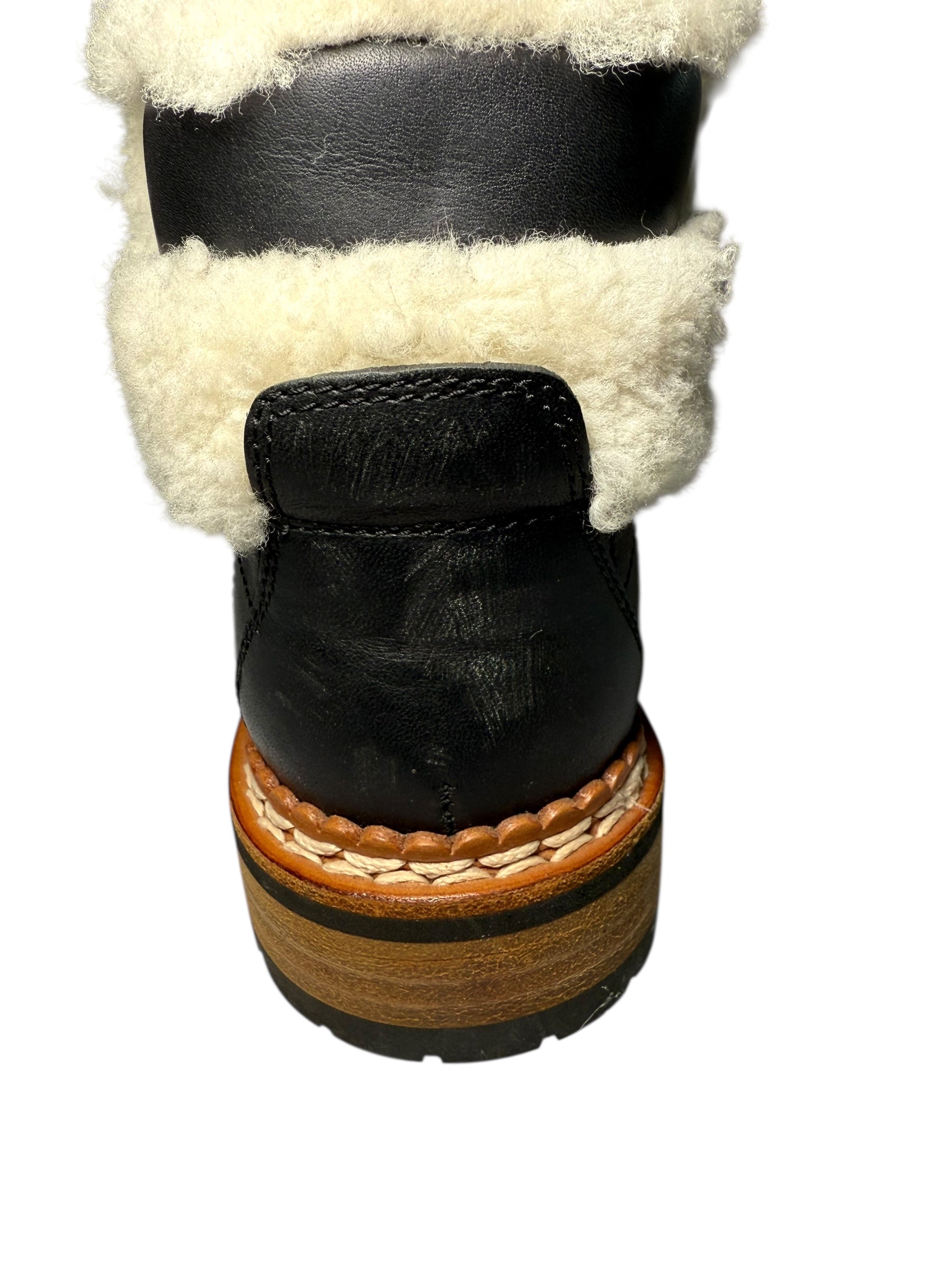 Chanel Black Quilted Leather With Shearling Lining Hiking Boots Left Heel detailing slight wear of black boot with white shearling lining and brown sole on a white background