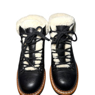 Pair of black quilted leather Chanel hiking boots with white fur lining front view on a white background