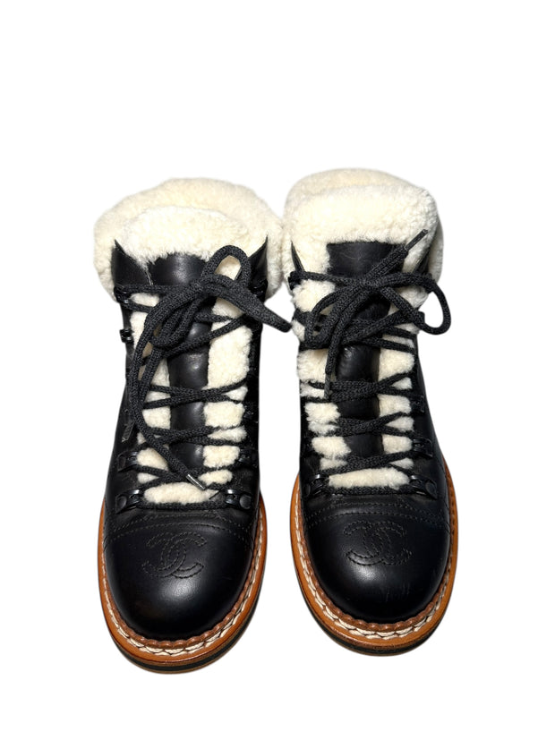 Pair of black quilted leather Chanel hiking boots with white fur lining front view on a white background