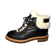Chanel Black Quilted Leather boot with white shearling trim and lining left shoe view on a white background