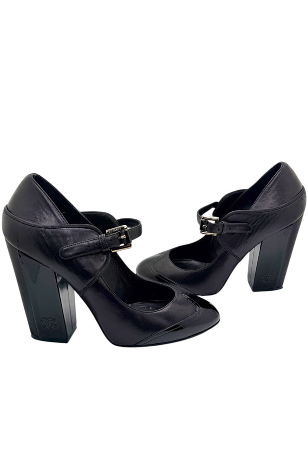 Side view of Chanel Mary Jane block heel pumps in black leather with adjustable strap and patent toe detail.