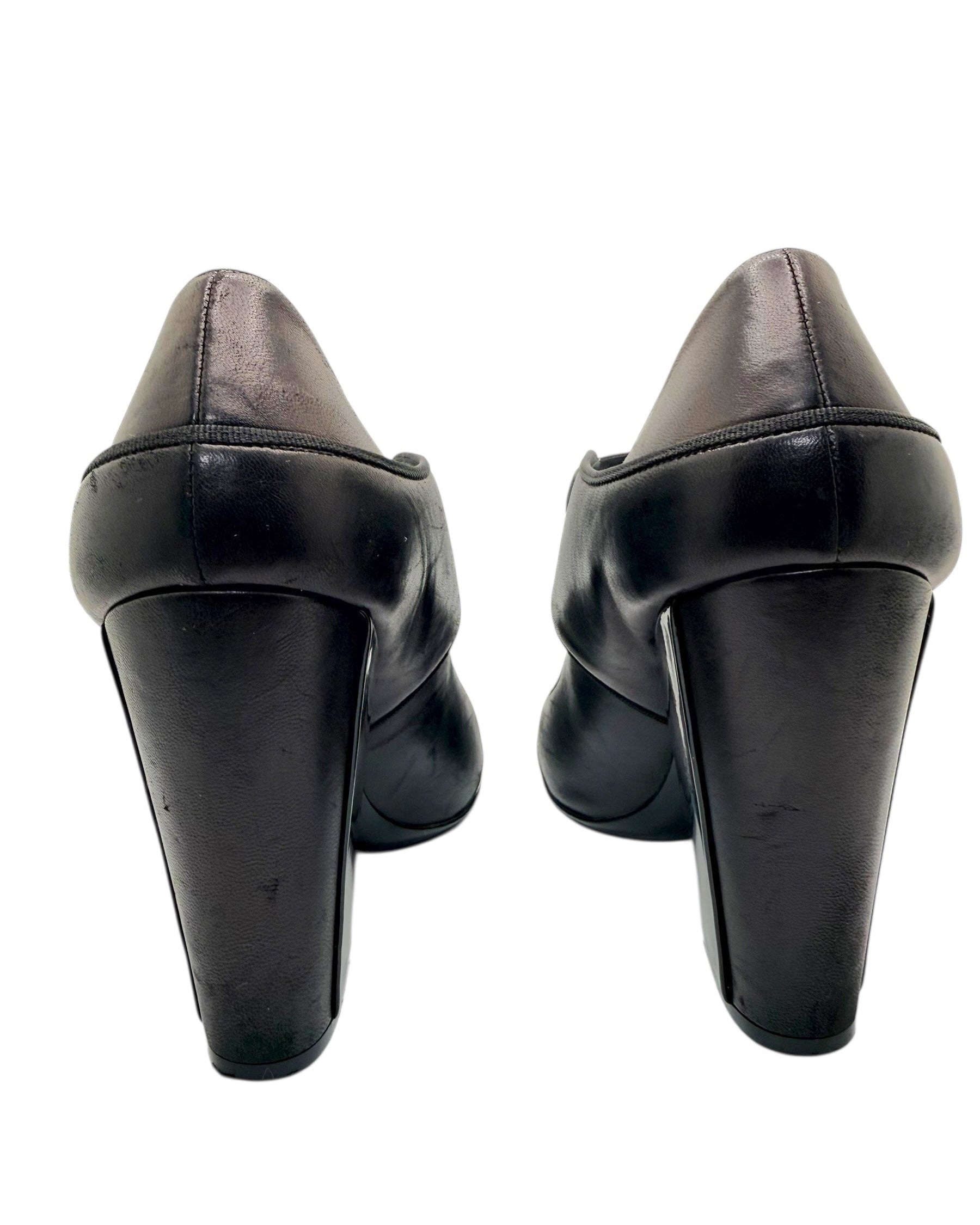 Close-up rear view of Chanel block heel pumps showing heel wear on leather finish.