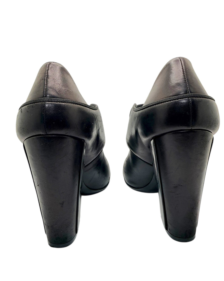 Close-up rear view of Chanel block heel pumps showing heel wear on leather finish.