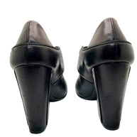 Close-up rear view of Chanel block heel pumps showing heel wear on leather finish.