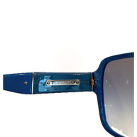 Close-up of Chanel metal logo plate on blue sunglasses temple.