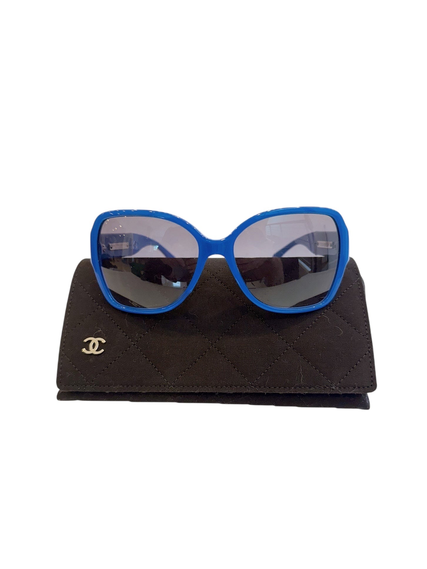 Chanel blue oversized sunglasses with gradient lenses displayed on black quilted Chanel case.