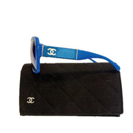 Chanel blue sunglasses left side showing white CC logo and thick acetate temple on case.