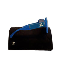 Side view of Chanel blue sunglasses showing white CC logo and wide temple on black case.