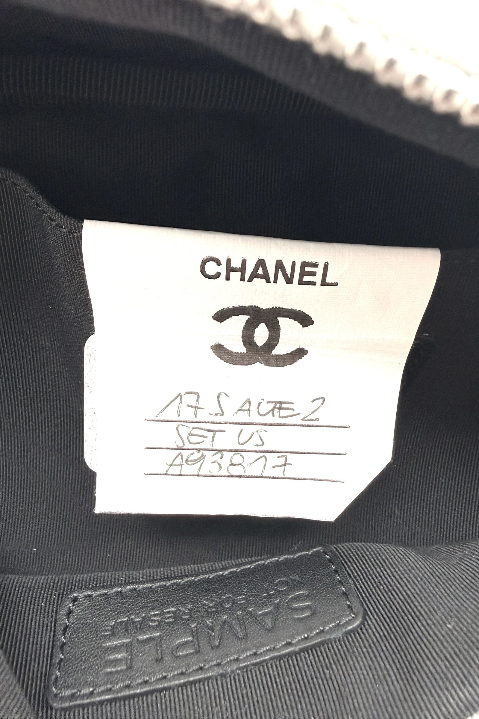 Interior close up of Chanel metallic silver bum bag showing sample label stitched into black lining, indicating production reference detail.