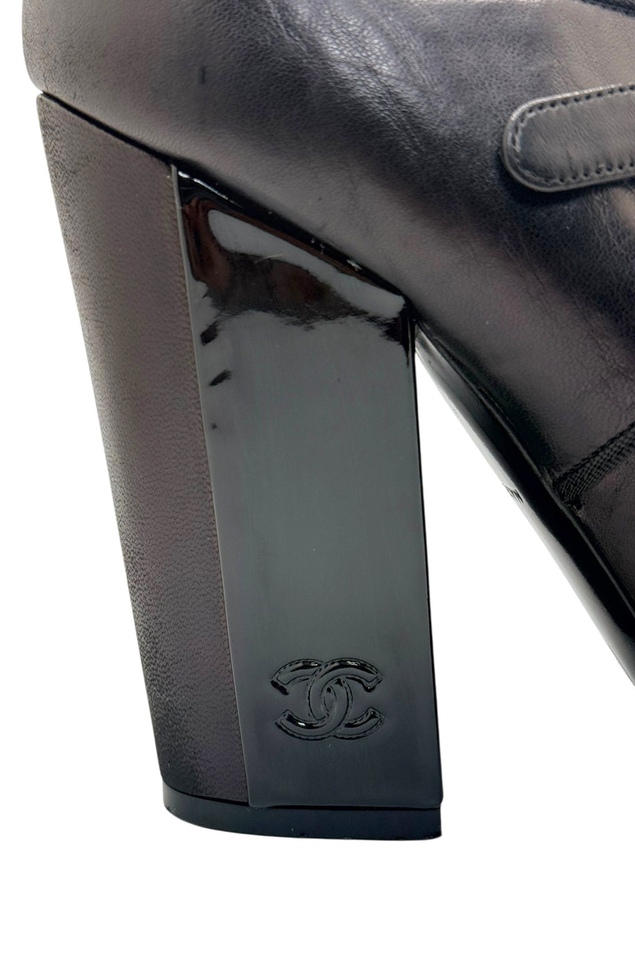 Chanel block heel detail with embossed CC logo on black leather Mary Jane pump.