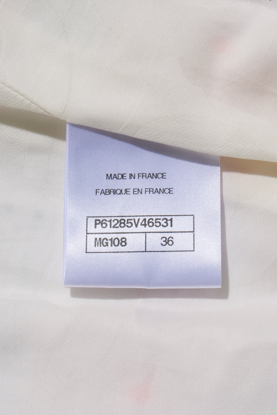 Chanel Fabrication label on a white fabric background with text 'MADE IN FRANCE' and product codes attached to Spring 2019 striped tweed coat.
