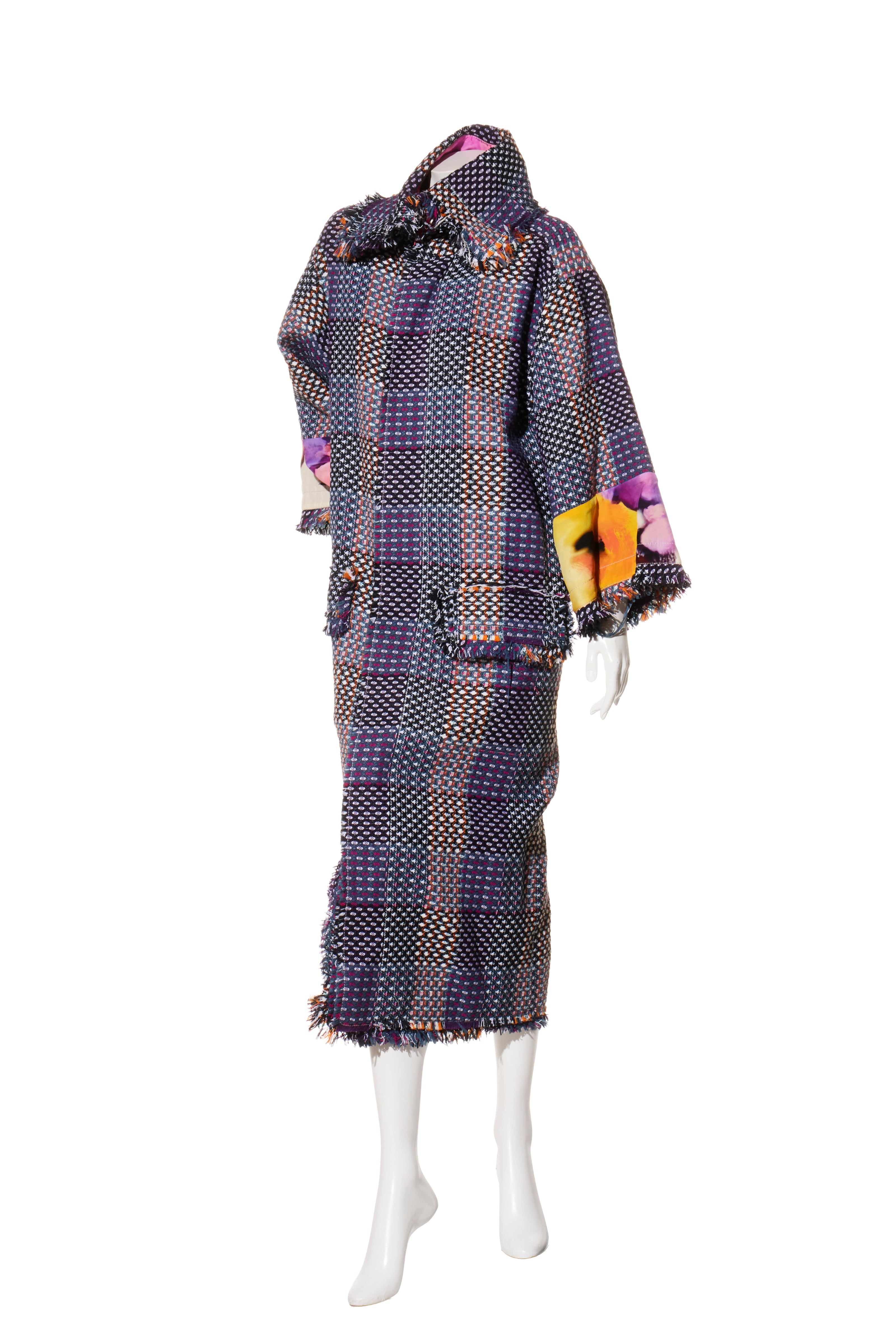 Chanel tweed coat with floral accents on a mannequin against a white background giving a left angle view