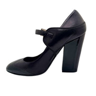 Front view of Chanel black leather Mary Jane pumps with glossy patent toe caps.