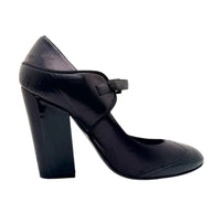 Full side view of Chanel Mary Jane pumps in black leather with patent toe and CC logo heel.