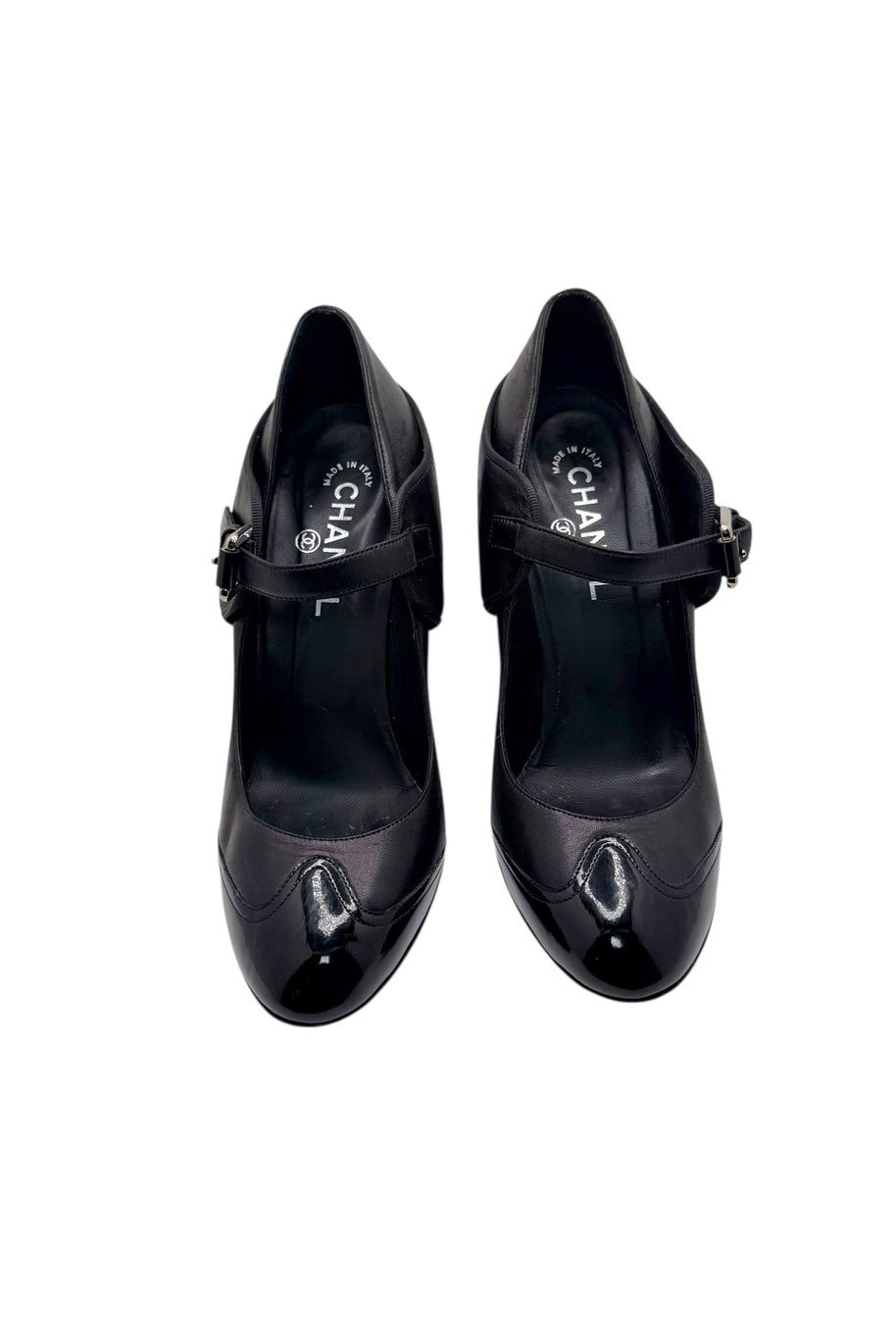 Top view of Chanel black leather Mary Jane pumps with patent toe caps and strap closure.