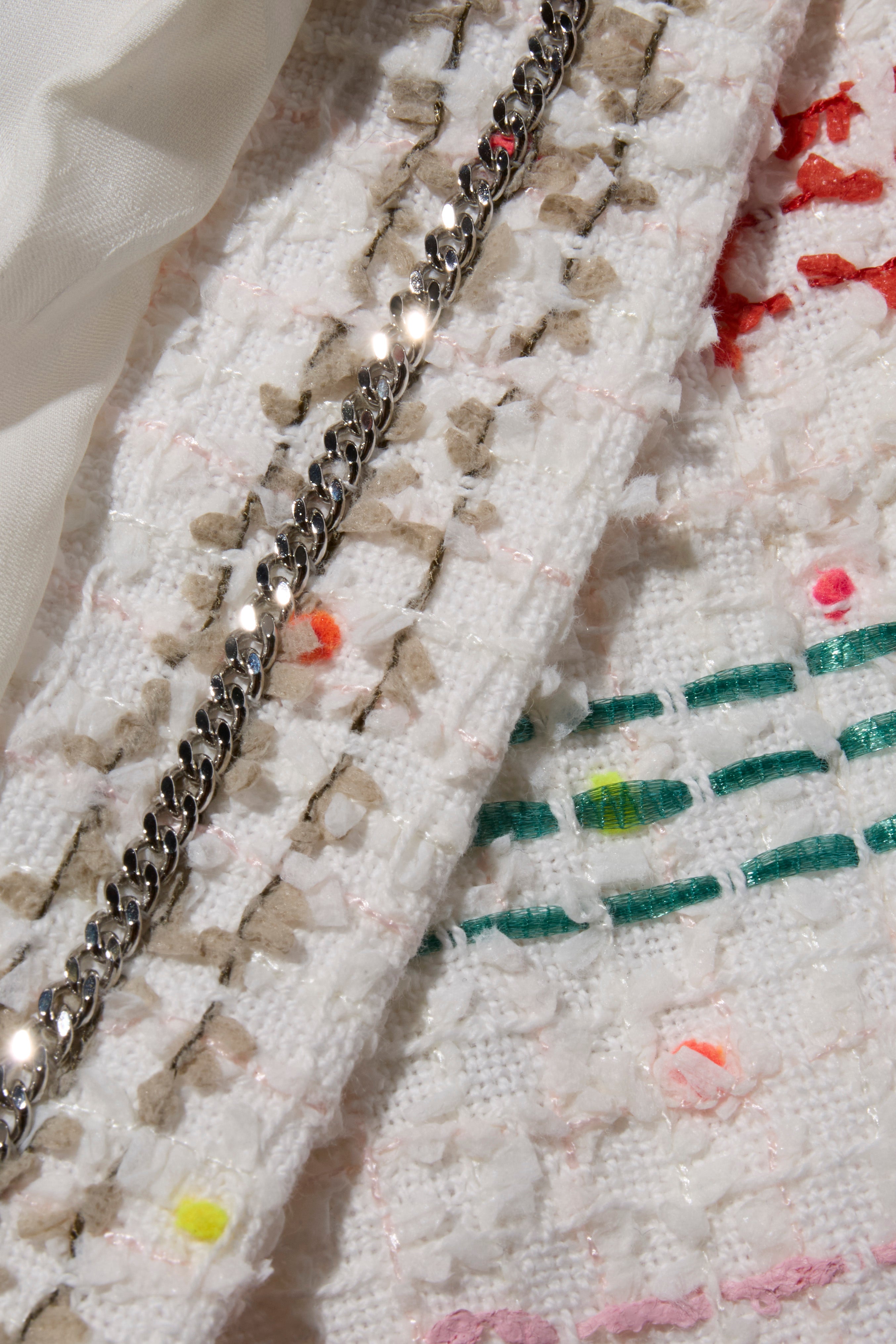 Close-up of Chanel tweed fabric with chain detail of Spring 2019 Coat by Karl Lagerfeld for Chanel.