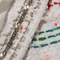 Close-up of Chanel tweed fabric with chain detail of Spring 2019 Coat by Karl Lagerfeld for Chanel.