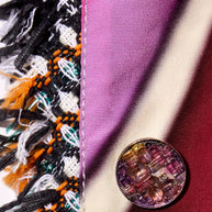 Close-up of Chanel reversible coat decorative button on fabric with fringe and floral print detail.