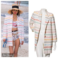 Model for Chanel 2019 Spring Collection Runway Show wearing a white Chanel with rainbow striped  detail tweed coat on a beach for reference, next to a mannequin wearing the same coat that is for sale.