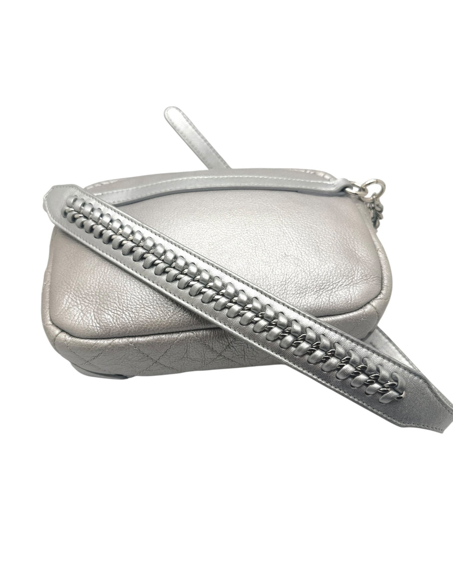 Close up of Chanel metallic silver bum bag showing leather interwoven chain strap detail and luxury hardware finish.