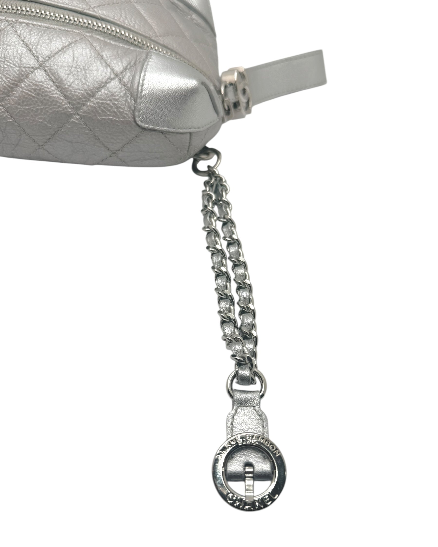 Close up of Chanel metallic silver bum bag showing leather interwoven chain strap detail and luxury hardware finish.