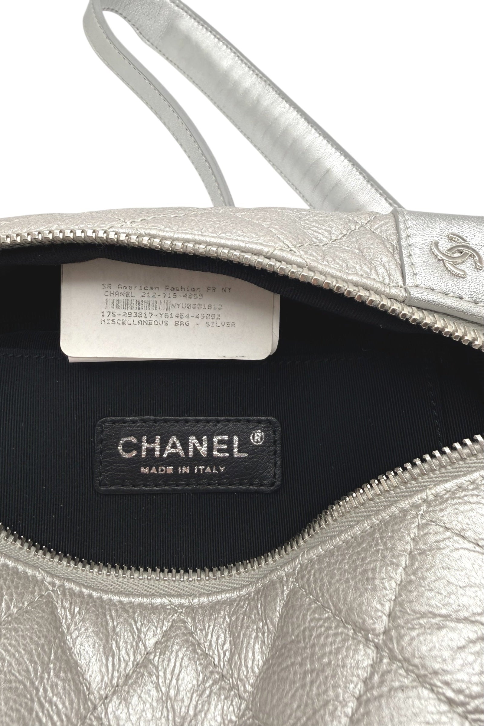 Close up of interior Chanel bum bag showing branded care tag, season marking, and authenticity identifiers inside black fabric lining.