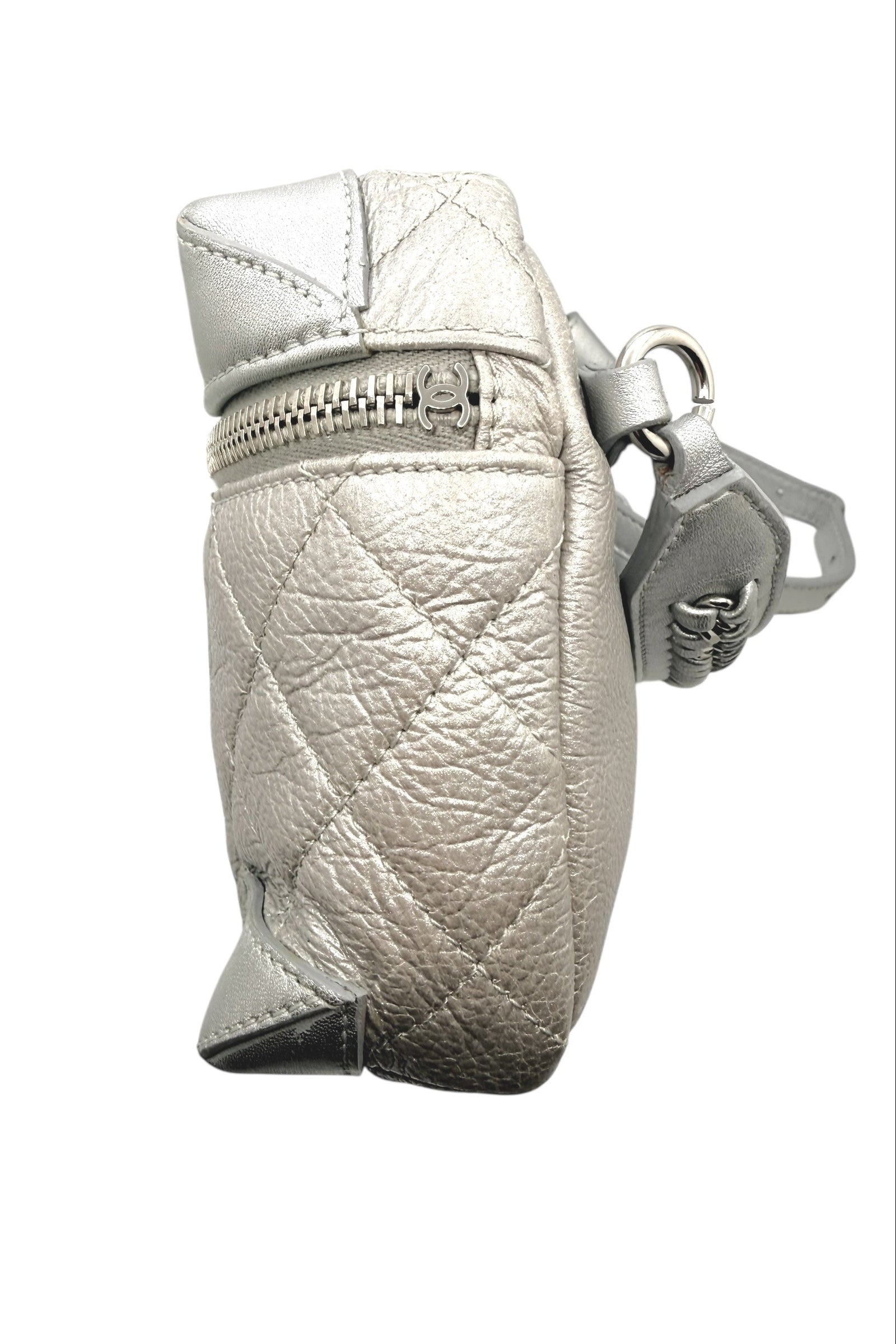 Side angle view of Chanel metallic silver quilted bum bag showing top zip closure with CC zipper pull and softly textured metallic leather.