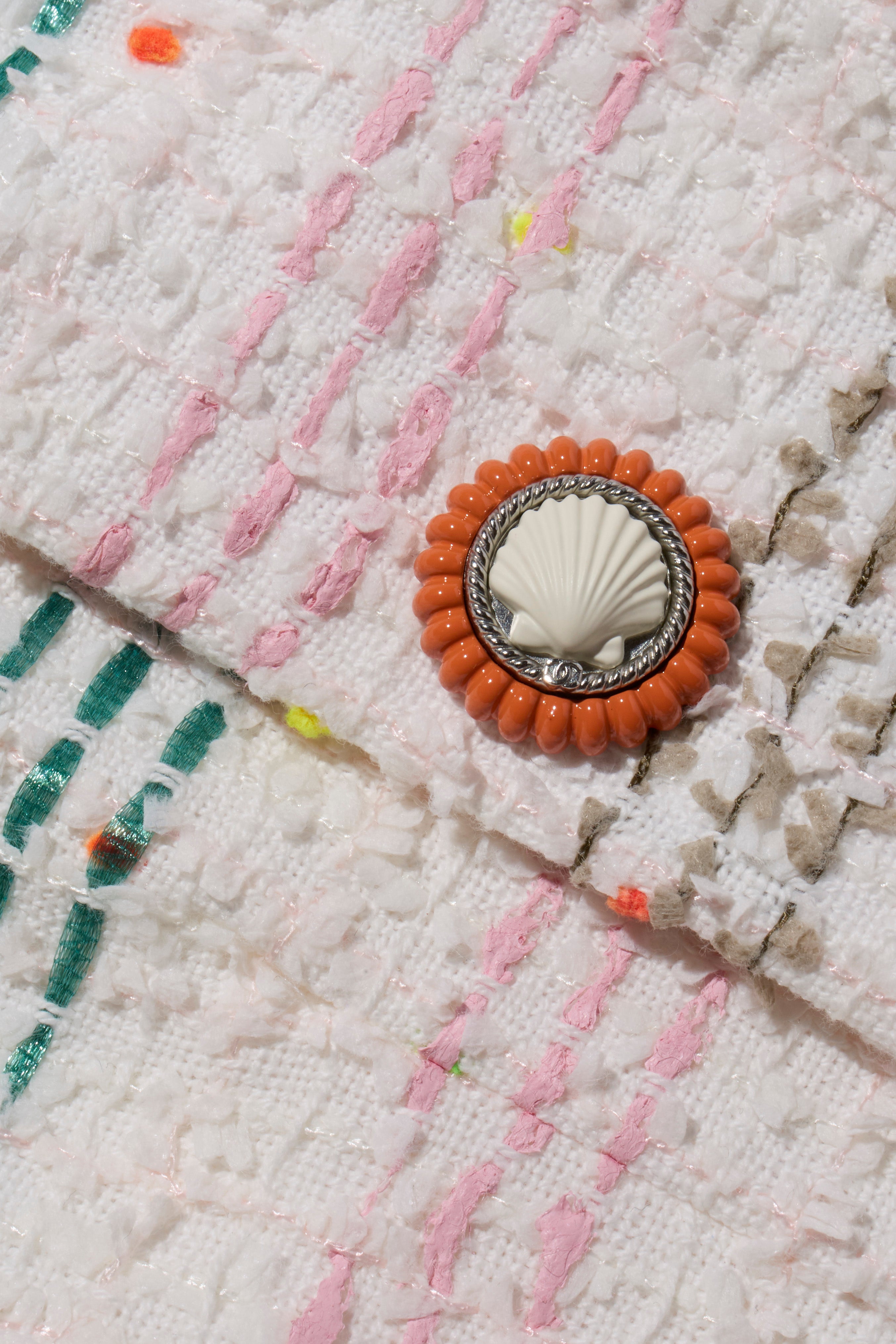 Close-up of decorative button with shell design on tweed coat of the rainbow Chanel coat from the Spring 2019 collection