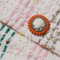 Close-up of decorative button with shell design on tweed coat of the rainbow Chanel coat from the Spring 2019 collection