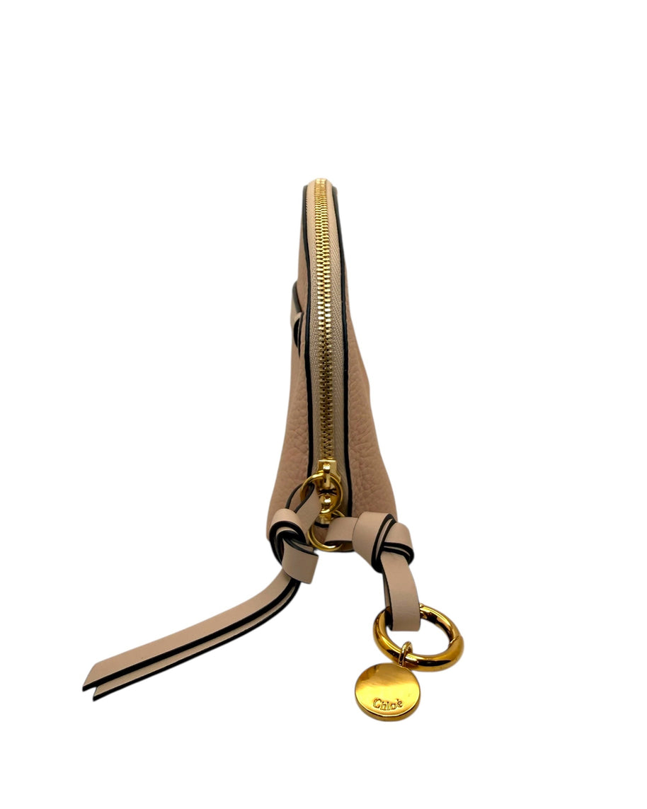 Side view of Chloé Alphabet pouch in blush calfskin featuring gold ring logo charm and leather wrist strap detail.