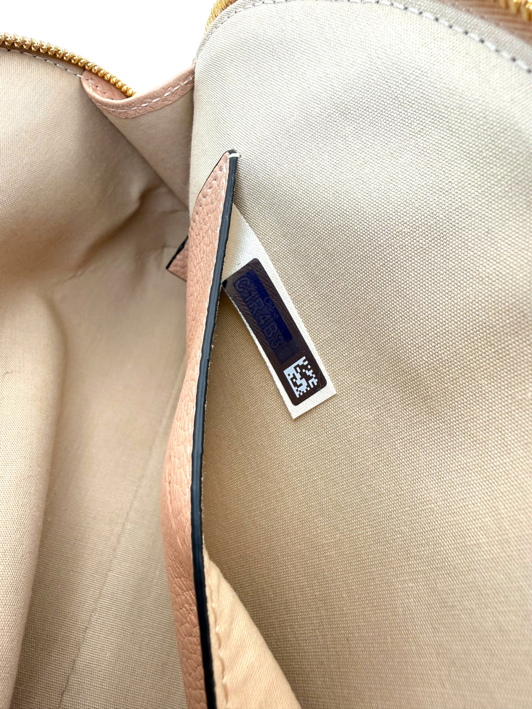 Close-up of interior authenticity hologram tag inside Chloé Alphabet blush leather pouch.