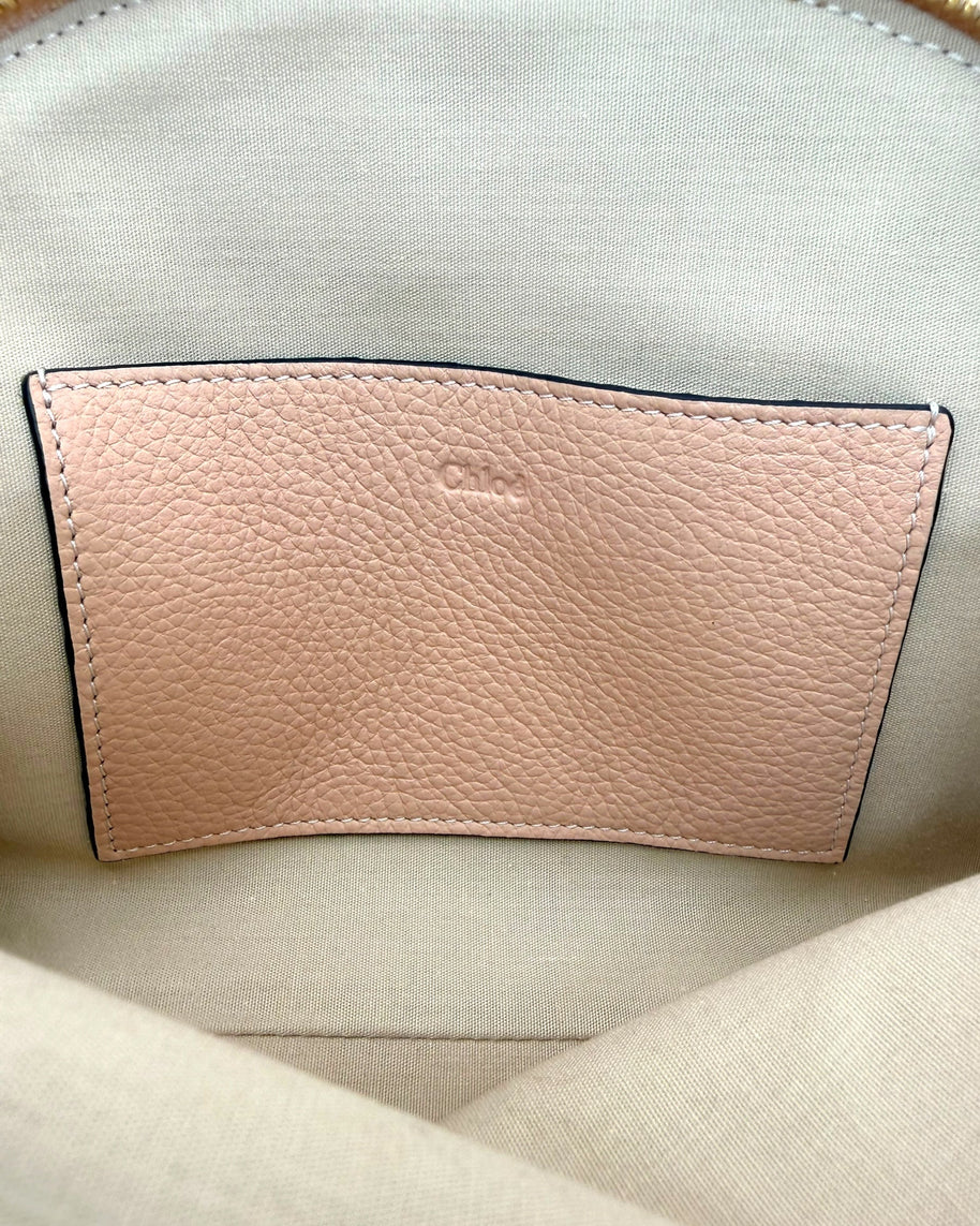 Interior of Chloé Alphabet blush leather pouch showing slip pocket with embossed Chloé logo on canvas lining.