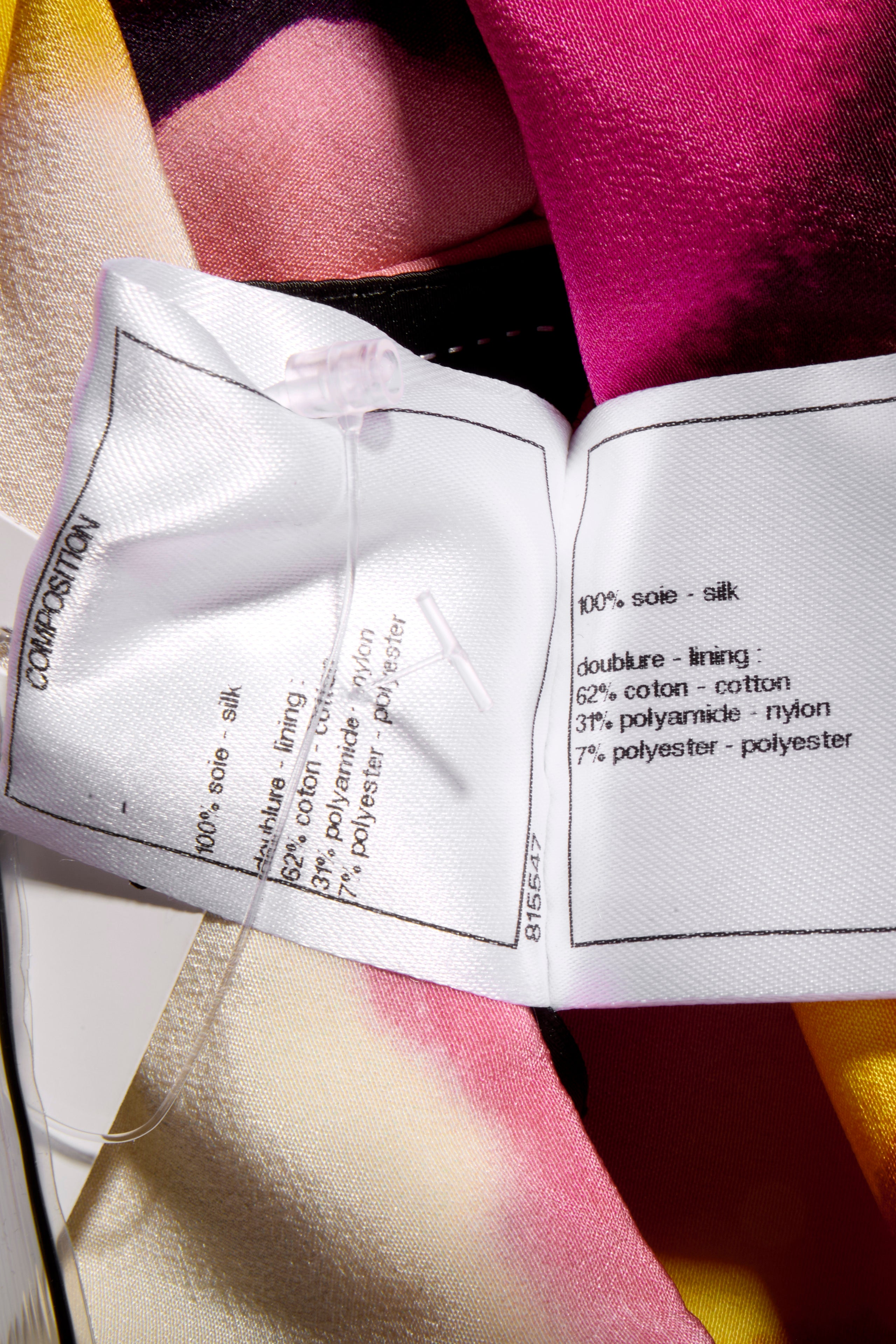 Close-up of Chanel fabric label wash tag with material composition details attached to the colorful floral fabric side of the coat.