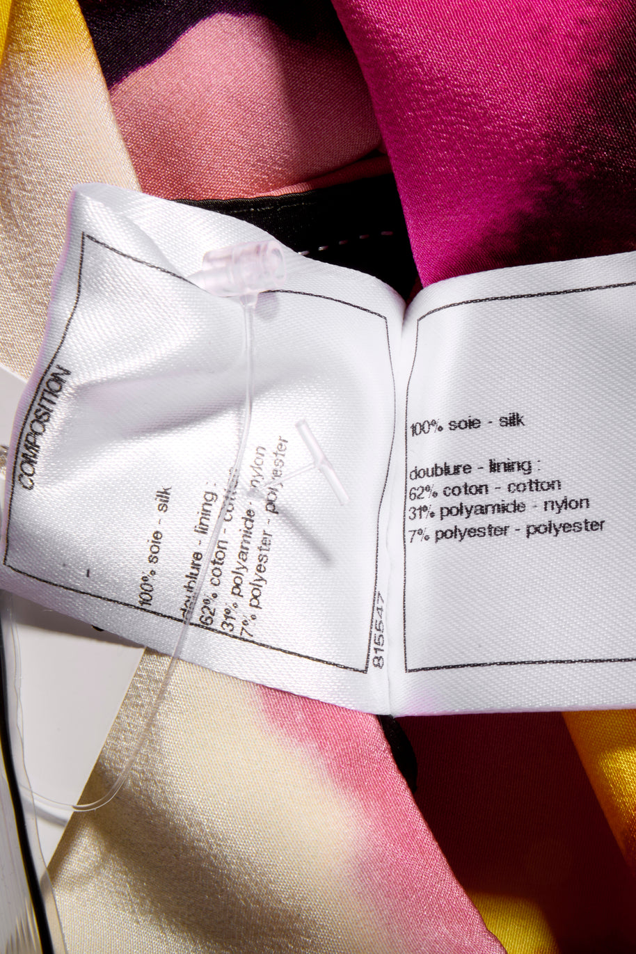 Close-up of Chanel fabric label wash tag with material composition details attached to the colorful floral fabric side of the coat.
