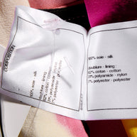 Close-up of Chanel fabric label wash tag with material composition details attached to the colorful floral fabric side of the coat.