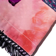 Chanel Close-up of a pink fabric with multi-color purple, pink, blue, black and white fringe on a white background