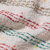 Close-up of multi color tweed fabric with red and green interwoven stitching on a white background of Chanel 2019 Tweed Coat