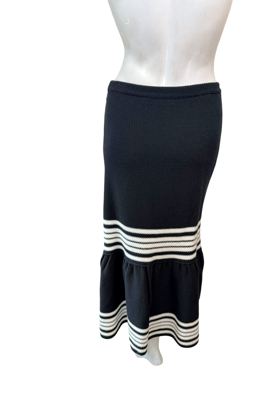 Back view of Dior black knit fluted midi skirt highlighting smooth fitted silhouette and ivory stripe accents.