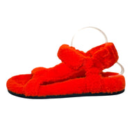 Side angled view of Fendi red shearling sandals highlighting crossover front straps and flat sole