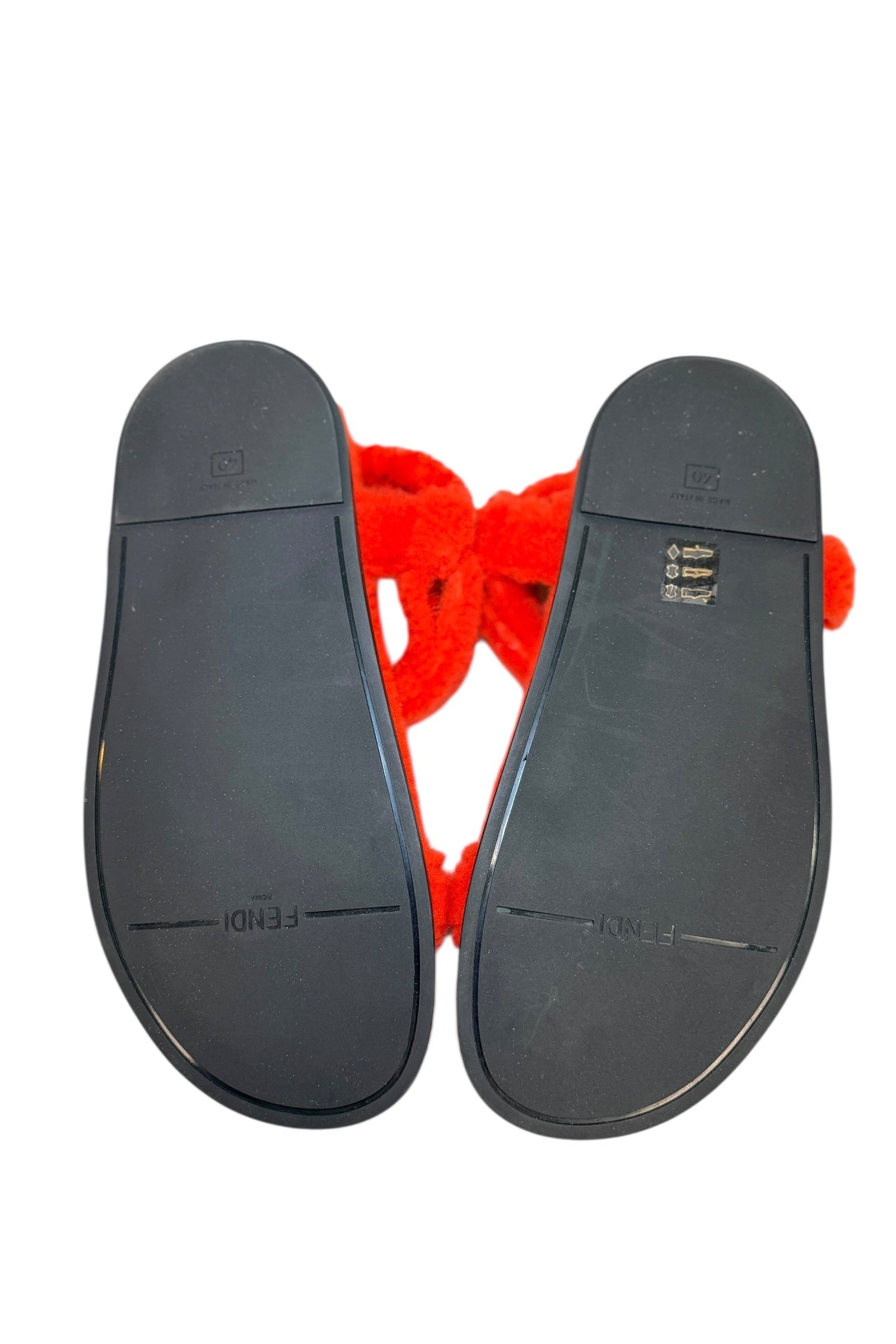 Bottom sole view of Fendi red shearling flat sandals with black rubber sole and Fendi branding