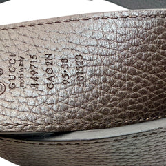 Close-up of reversible brown leather Gucci belt with visible branding and numbers.