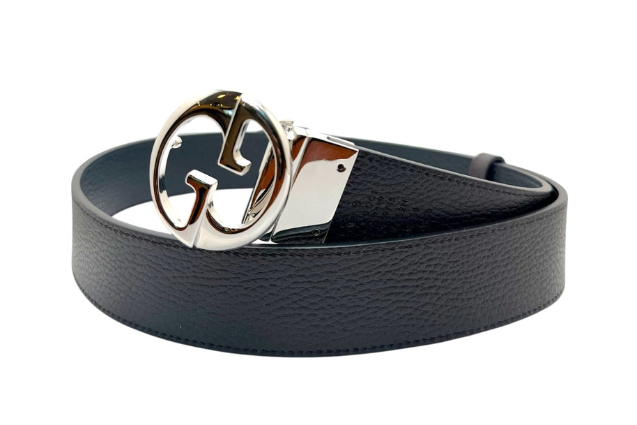 Angled hero view of Gucci black leather Interlocking G belt, luxury GG buckle accessory made in Italy.
